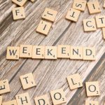 Wooden Scrabble tiles spelling 'weekend' on a rustic wooden table.