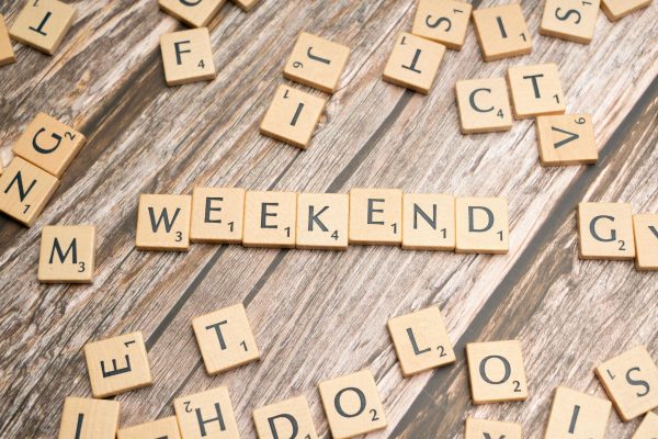 Wooden Scrabble tiles spelling 'weekend' on a rustic wooden table.